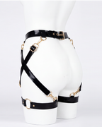 A glossy black latex waist and leg harness set by Ribcage, featuring structural straps, metallic O-rings, and adjustable buckles.