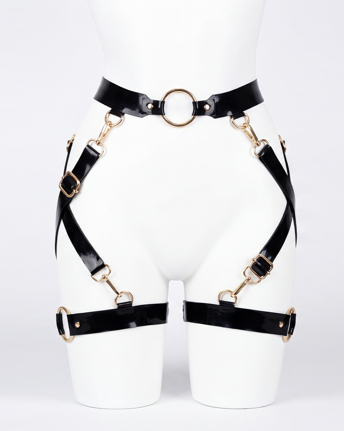 A glossy black latex waist and leg harness set by Ribcage, featuring structural straps, metallic O-rings, and adjustable buckles.