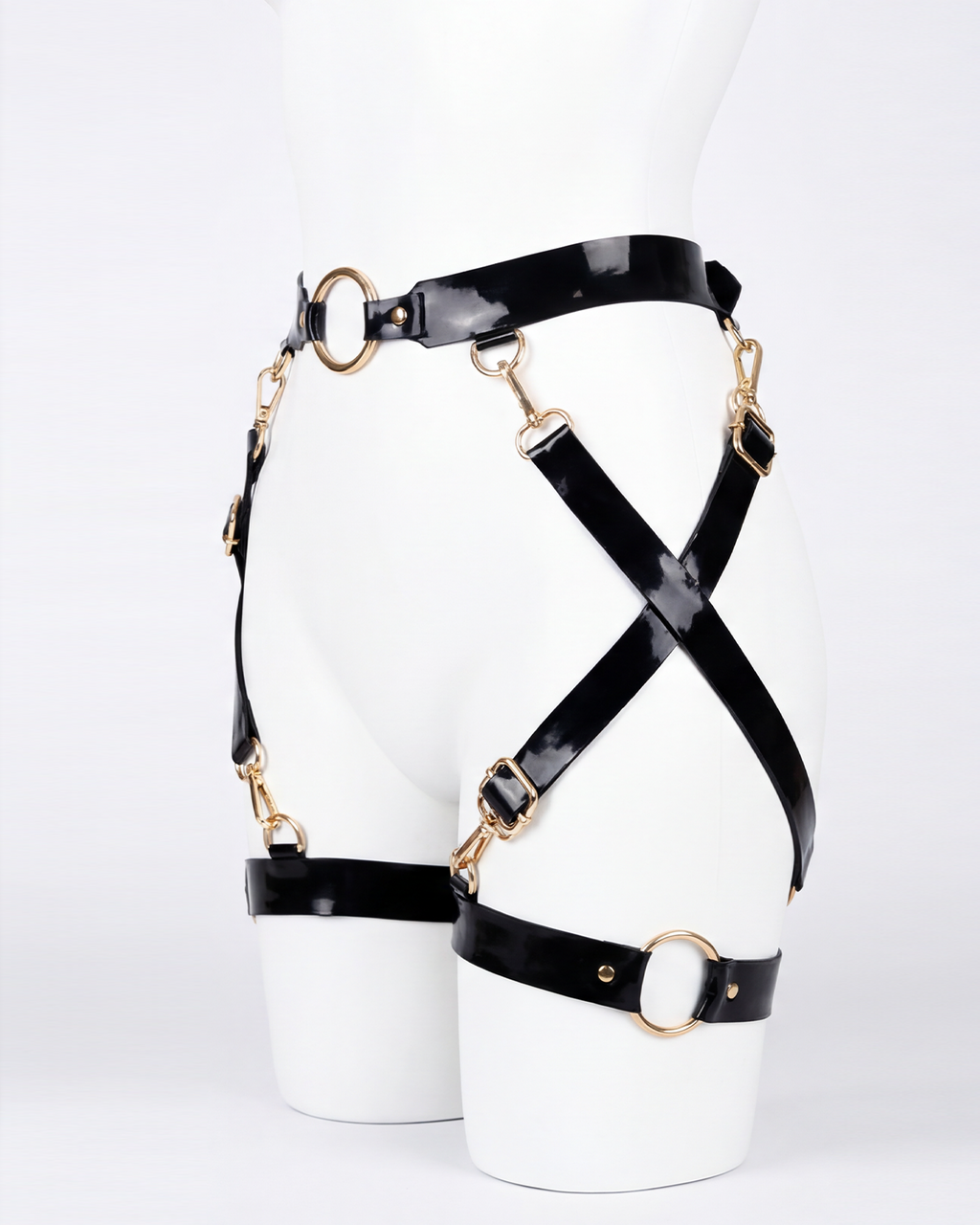A glossy black latex waist and leg harness set by Ribcage, featuring structural straps, metallic O-rings, and adjustable buckles.