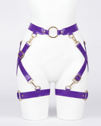 A glossy purple latex waist and leg harness set by Ribcage, featuring structural straps, metallic O-rings, and adjustable buckles.