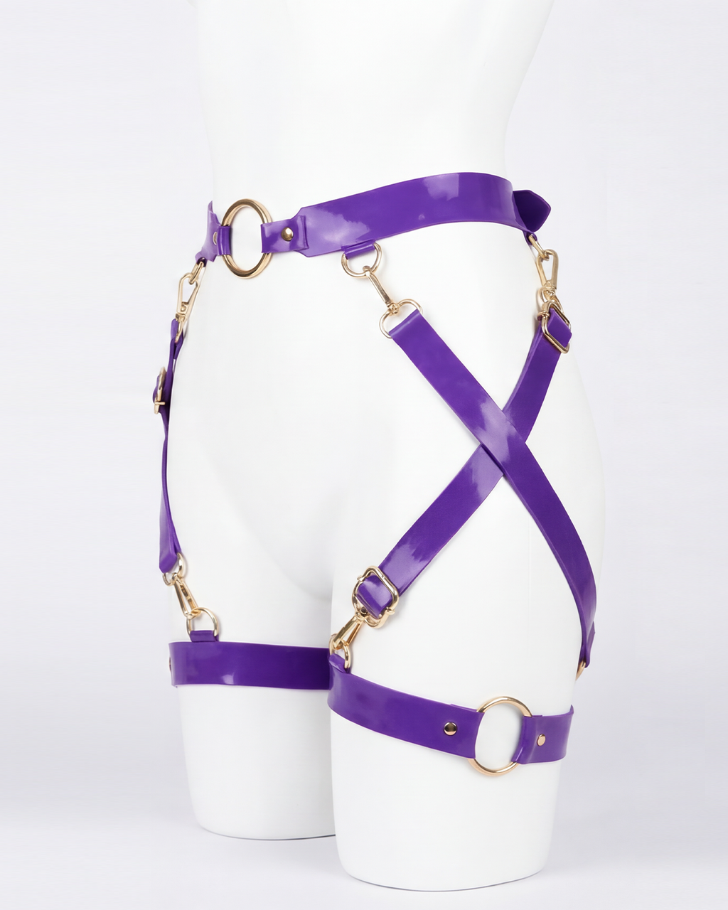 A glossy purple latex waist and leg harness set by Ribcage, featuring structural straps, metallic O-rings, and adjustable buckles.