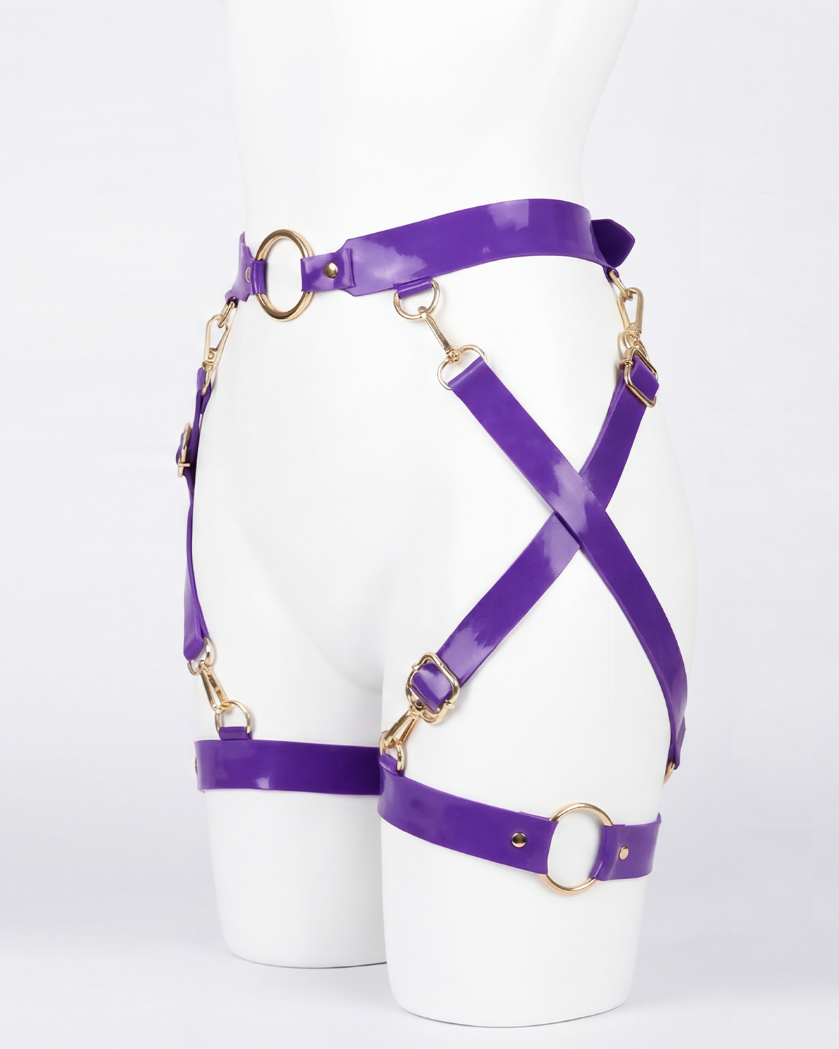 A glossy purple latex waist and leg harness set by Ribcage, featuring structural straps, metallic O-rings, and adjustable buckles.