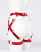 A glossy red latex waist and leg harness set by Ribcage, featuring structural straps, metallic O-rings, and adjustable buckles.