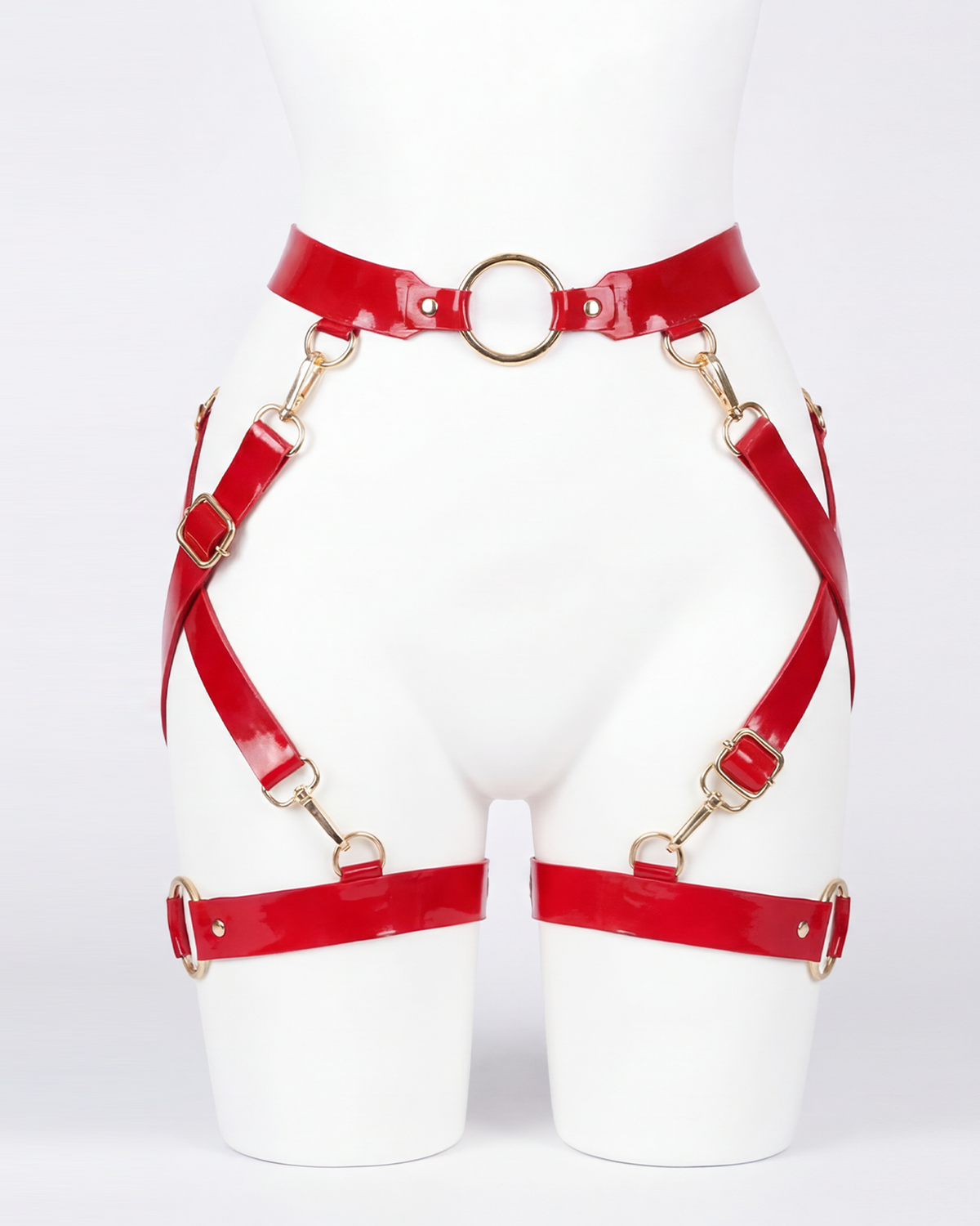 A glossy red latex waist and leg harness set by Ribcage, featuring structural straps, metallic O-rings, and adjustable buckles.