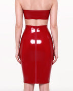 A model shown from the back wearing a high-shine red latex high-waisted pencil skirt by Ribcage, featuring a full-length back zipper closure, styled with a red strapless latex bandeau top.