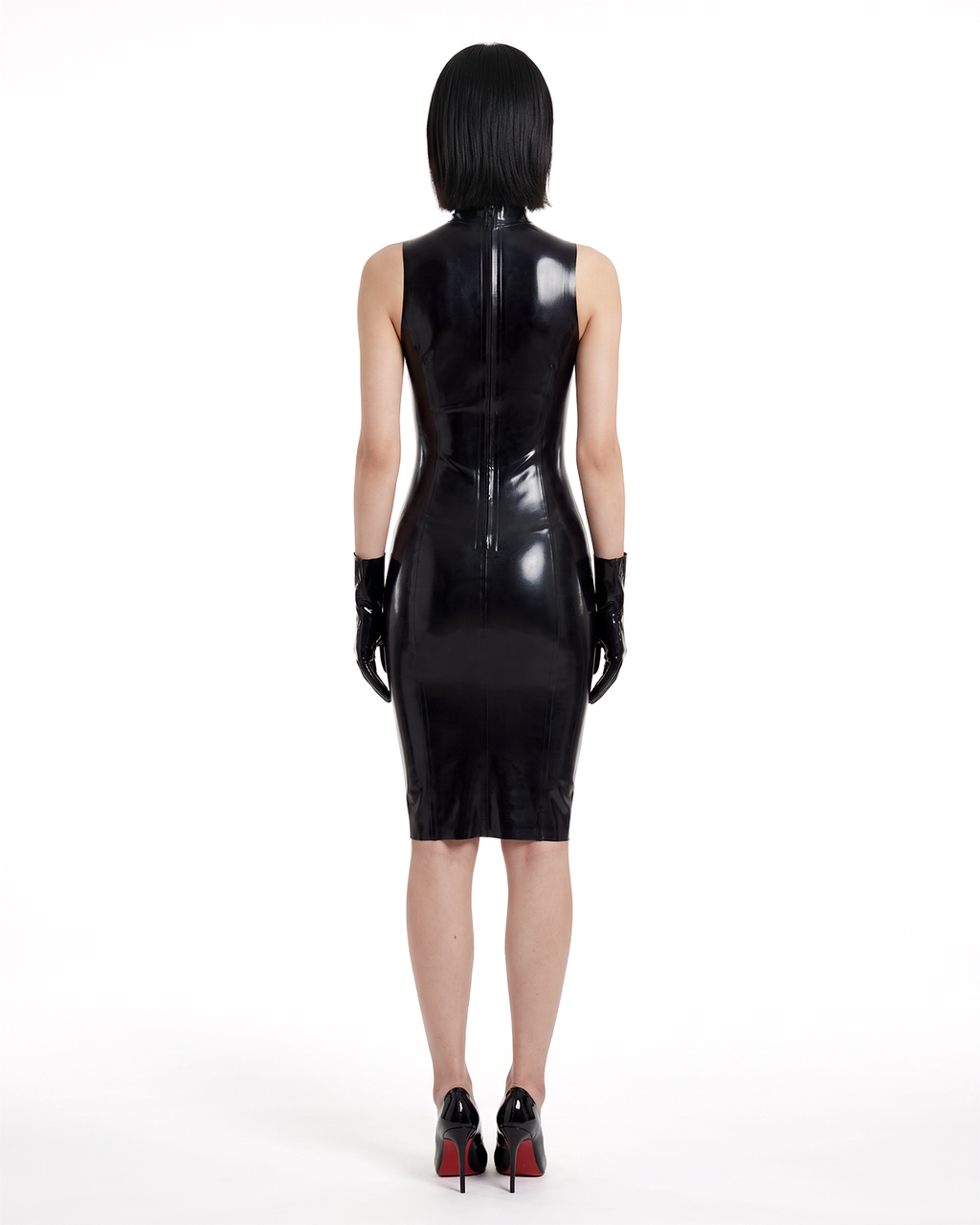 A model shown from the back wearing the high-shine black latex The Arbiter Dress by Ribcage Latex, featuring contoured seaming, a half-length back zipper, and a knee-length compressive cut.