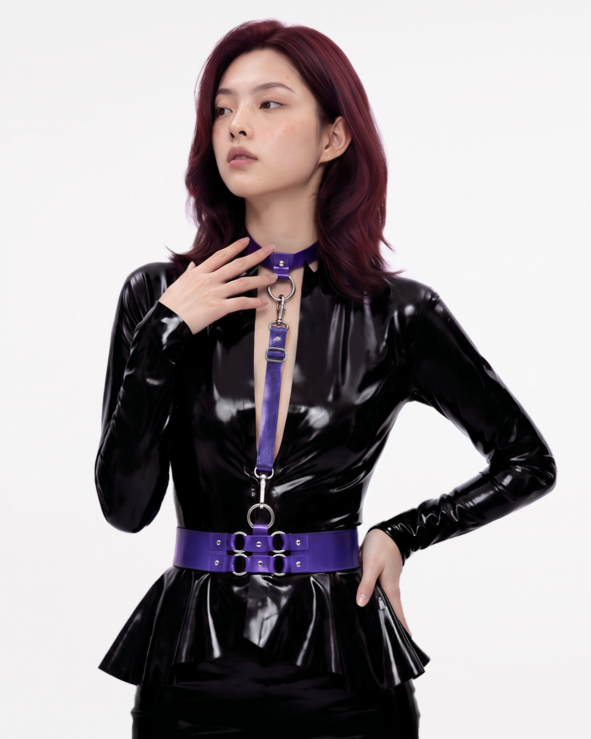 A model shown from the front wearing The Aurora Harness Set in metallic purple latex over a black latex dress, featuring a buckled choker, vertical chest strap, and a structured waist belt, accented with silver metallic O-rings and hardware.