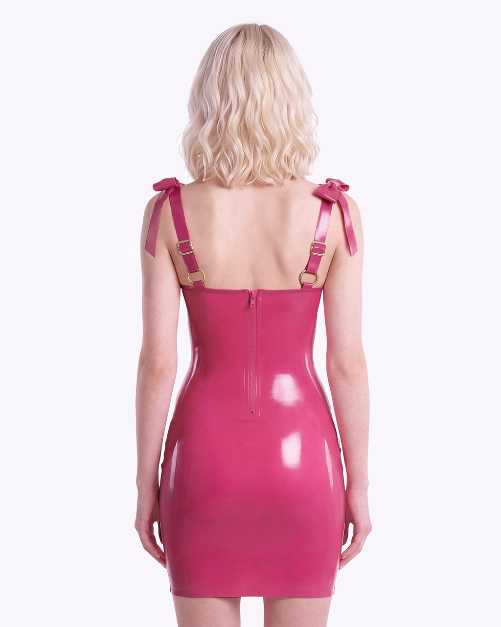 A model shown from the back wearing a high-shine vivid fuchsia latex bodycon slip dress by Ribcage, featuring a sweetheart neckline with structural piping, a metallic pink center bow, and matching metallic pink structural bows on the shoulder straps.