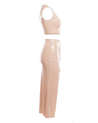 A high-shine nude latex two-piece ensemble by Ribcage, featuring a minimalist sleeveless crop top and a high-waisted maxi skirt with a dramatic side slit and a polished metal buckle accent, designed with a compressive second-skin fit.