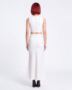 A model shown from the back wearing a high-shine white latex two-piece ensemble by Ribcage, featuring a minimalist sleeveless crop top, a high-waisted maxi skirt, and a compressive second-skin fit.