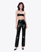 A full-body view of a model wearing the high-shine black latex Phantom Straight-Leg Trousers by Ribcage, showcasing the sharply tailored silhouette and sculptural drape.