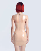 A model shown from the back wearing a high-shine nude latex dress by Ribcage, featuring a scoop neckline, sleeveless sheer transparent shoulders, opaque body panels, and a compressive second-skin pencil silhouette.