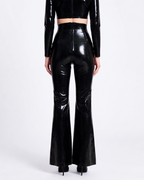 A model shown from the back wearing a pair of glossy metallic black latex high-waisted flared trousers by Ribcage, featuring a sharp architectural drape and a compressive second-skin fit that accentuates the silhouette.