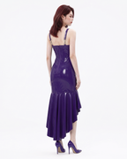 A model shown from the back wearing a high-shine purple latex mermaid dress by Ribcage, highlighting the adjustable straps and cascading flounce hem.