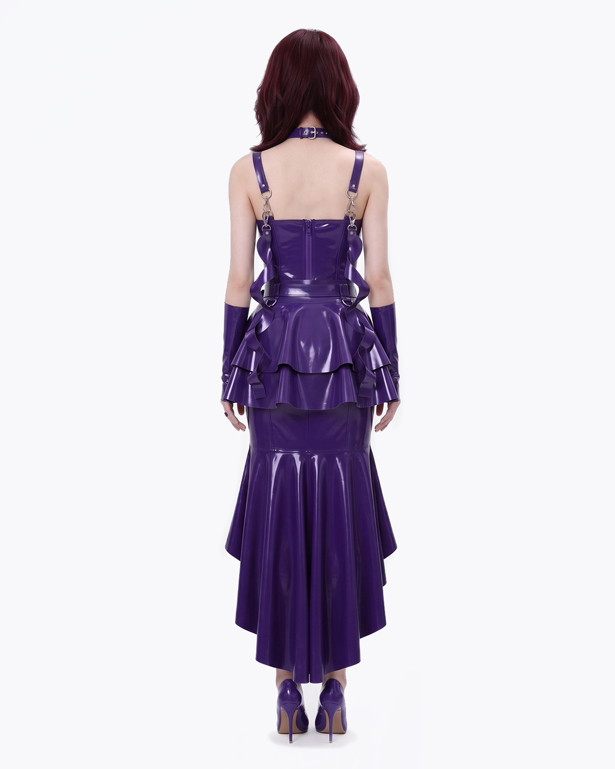 A model shown from the back wearing a high-shine purple latex multi-piece suit by Ribcage, featuring a form-fitting dress layered with the modular metallic purple Aurora Peplum Overlay, a matching choker, and coordinating long gloves.