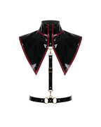 A glossy black latex modular capelet harness set by Ribcage, featuring a high-neck triangular capelet with contrast red trim, a vertical chest strap, and a waist belt with metallic O-rings.